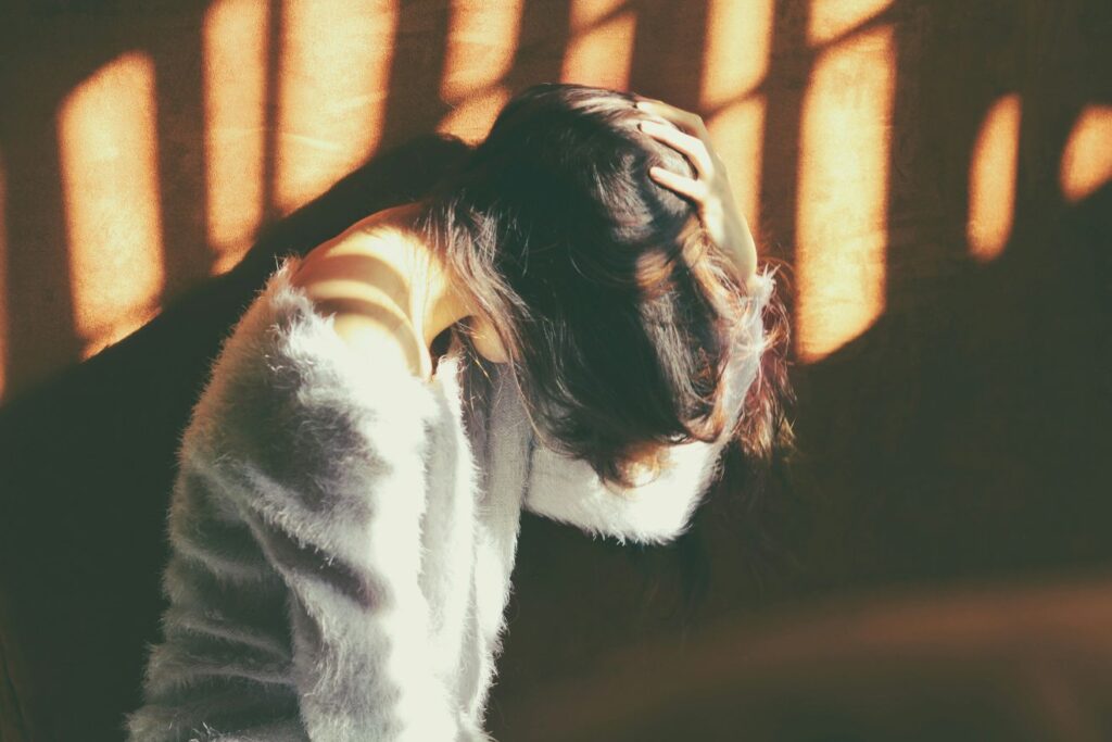 person looking down with her hand on her head